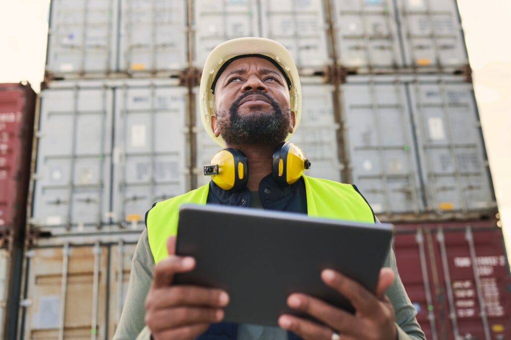 Logistics, tablet and black man doing container inspection at an industrial cargo, shipping and fre